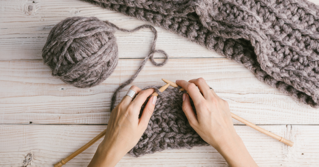 Hands with knitting needles and yarn